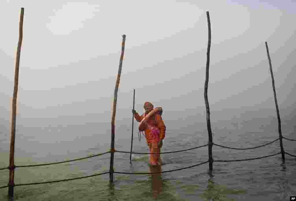 An Indian Hindu volunteer carries a life preserver as he watches the fence line in the bathing area at Sangam at the start of Kumbh Mela in Allahabad, India, January 14, 2013.