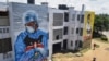 Residents in Mombassa, Kenya, walk in front of informational murals painted on the side of an apartment block about the coronavirus and paying tribute to medical workers with the messages "We'll Protect You" and "We Salute You," Aug. 17, 2020.