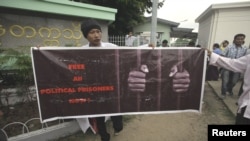 A man holds a poster calling for the freedom of political prisoners in front of the Rangoon University where U.S. President Barack Obama was giving a speech, November 19, 2012.