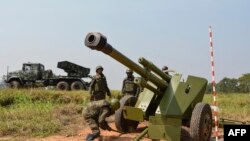 Des soldats des forces armées de la République démocratique du Congo (FARDC) installent une pièce d'artillerie mobile (Front) à côté d'un lance-roquettes multiples mobile à Matombo, à 35 km au nord de Beni, au Nord Kivu, le 13 janvier 2018.
