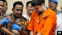 Denpasar police chief Ruddi Setiawan (C-L) holds a two-year-old male orangutan as Russian Andrei Zhestkov (R) stands during a press conference in Bali, Indonesia on March 25, 2019. 