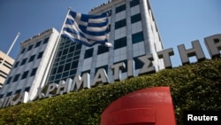 FILE - A Greek flag flutters outside the Athens stock exchange, Greece.