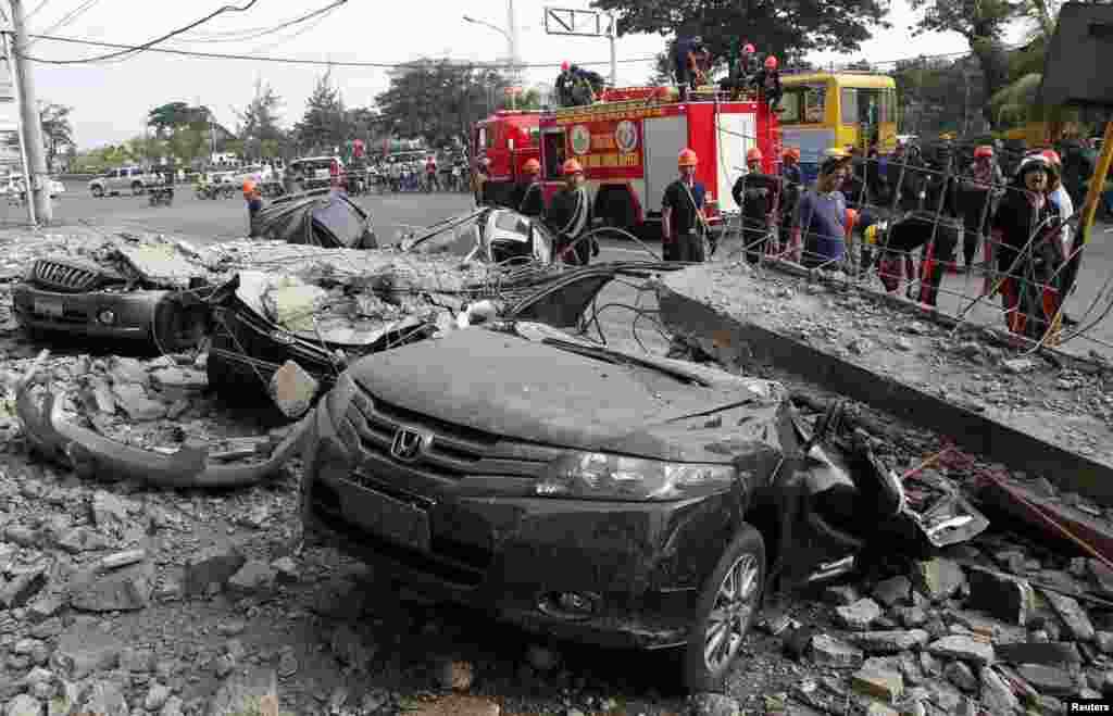 Firefighters stand near damaged vehicles after an earthquake struck Cebu city, in central Philippines, Oct. 15, 2013.