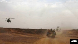 FILE - A helicopter of the French army escorting a vehicle transporting Mali's Prime Minister Moussa Mara from Gao to Kidal, May 17, 2014.