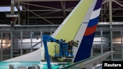 FILE - Boeing employees work on the tail of a Boeing 737 NG at the Boeing plant in Renton, Washington, Dec. 7, 2015. 