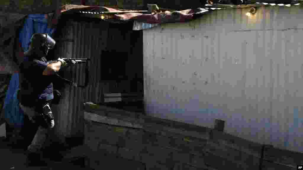 Un policier armé prend prosition près d’une auberge à Astonville, près de Johannesburg, jeudi 16 Avril 2015 lors d'une manifestation anti-immigrés. 