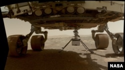L'hélicoptère Ingenuity de la NASA est visible ici avec ses quatre pattes déployées avant de se laisser tomber du ventre du rover Persévérance le 30 mars 2021.