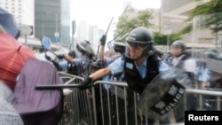 Waandamanaji wakikabiliana na polisi wa kuzuia ghasia wakati wa maandamano ya kupinga pendekezo la sheria ya kuwarudisha raia kujibu mashtaka nchini kwao karibu na bunge la Hong Kong, China Juni 12, 2019. REUTERS/Thomas Peter