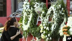 Family members of a victim of the Casino Royale's deadly arson attack stand at a makeshift memorial, in front of the charred gambling house in Monterrey, Mexico, August 27, 2011