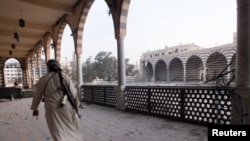 A Free Syrian Army fighter walks with his weapon through the damaged Khalid Ibn Al-Walid Mosque in Homs, June 30, 2013 file photo. 
