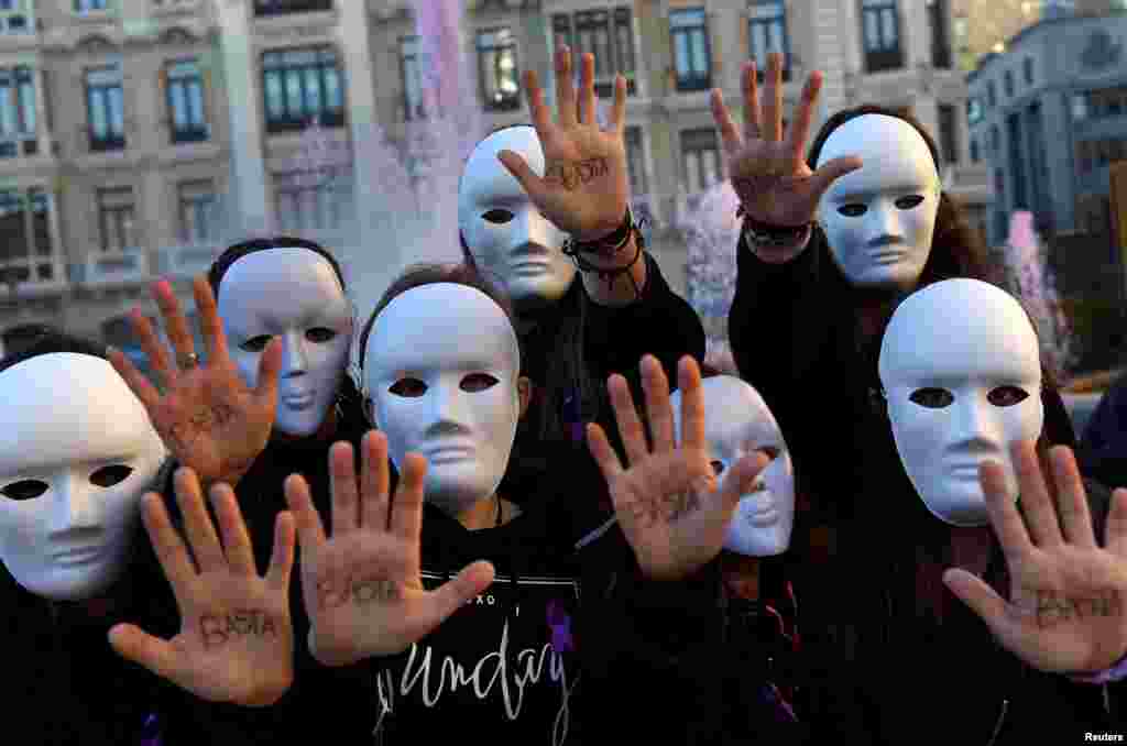 Para mahasiswa jurusan studi gender memakai masker dan menunjukkan telapak tangan mereka yang bertuliskan kata "Cukup" dalam pertunjukan untuk memperingati Hari Internasional untuk Penghapusan Kekerasan Terhadap Perempuan di Oviedo, Spanyol (25/11). (Reuters/Eloy Alonso)