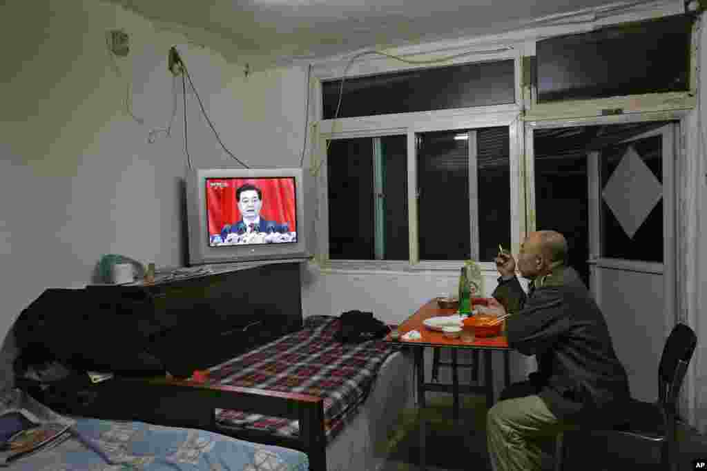 2012年11月8日，一位男士在北京的家里一边吃饭一边观看中共总书记胡锦涛在18大开幕式上发表讲话的新闻。