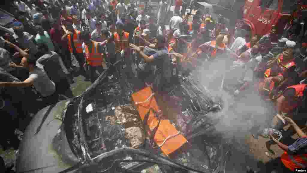 Palestinians gather around the remains of a car, which witnesses said was hit by an Israeli airstrike, in Gaza City, Aug. 24, 2014.