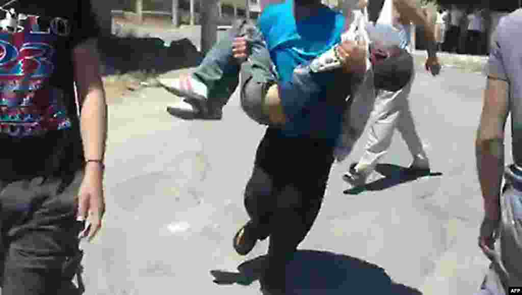 An taken from a video uploaded on YouTube on June 8, 2012 shows a Syrian man rushing a wounded boy to an ambulance in the southern Syrian city of Daraa.