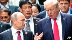 FILE - U.S. President Donald Trump and Russia's Presiden Vladimir Putin berbicara dengan Presiden Donald Trump dalam acara foto bersama di APEC di Danang, Vietnam, 11 November 2017. 