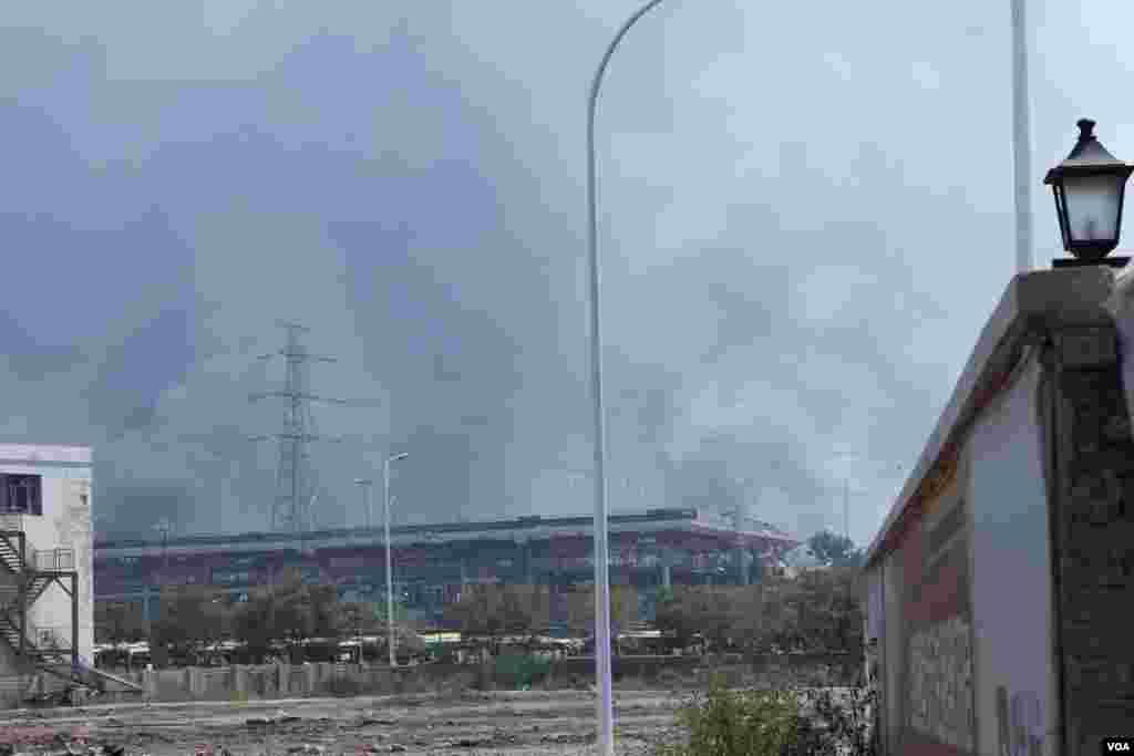 天津爆炸事故現場,核心爆炸區週圍多座居民樓窗戶被震碎,高速公路橋樑受損,多輛大貨車被炸翻,小汽車起火或被砸,多名當地居民仍逗留在事故現場。(美國之音記者東方拍攝)