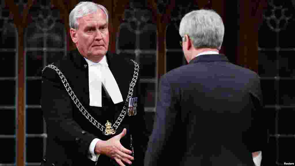 Prime Minister Stephen Harper shakes hands with Sergeant-at-Arms Kevin Vickers, who shot and killed a gunman who had rampaged through the parliament building, in the House of Commons in Ottawa, Oct. 23, 2014.
