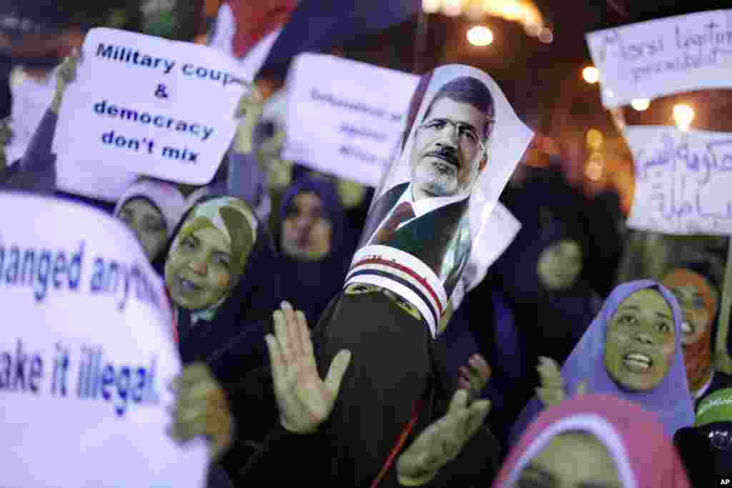 Para pendukung presiden Mesir yang digulingkan, Mohamed Morsi, meneriakkan slogan-slogan sambil membawa poster bergambar Morsi di depan Cairo University (16/7). (AP/Amr Nabil)