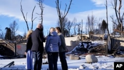 President Joe Biden and first lady Jill Biden talk with people as they tour a neighborhood in Louisville, Colo., Jan. 7, 2022, that was impacted by the recent wildfire. At left is Colorado Gov. Jared Polis. 