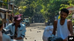 Para pekerja kereta api meninggalkan rumah dinas saat melakukan aksi mogok, sementara polisi mengawasi mereka di Yangon, Myanmar, Rabu (10/3). 
