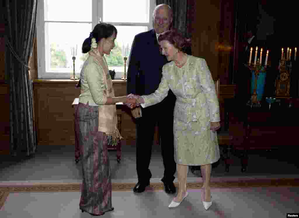 Nobel Peace Prize laureate Aung San Suu Kyi is greeted by Norwegian King Harald and Norway's Queen Sonja (L-R) at the Royal Castle in Oslo, June 16, 2012.