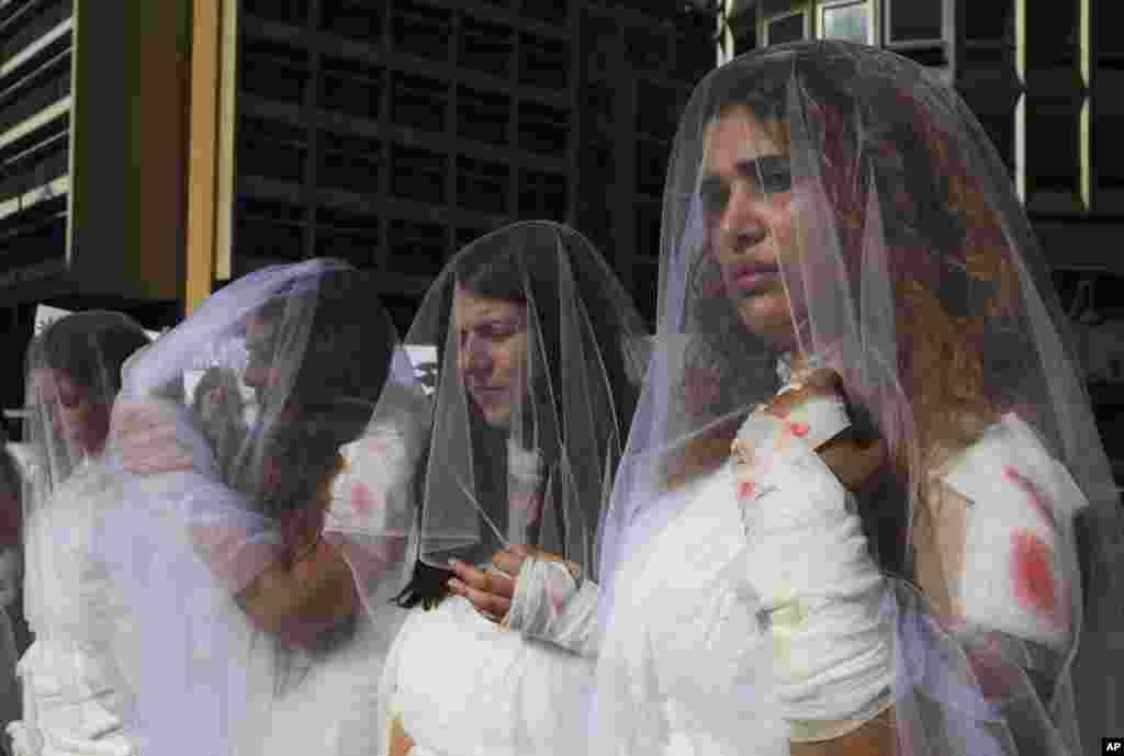 Para perempuan Lebanon mengenakan gaun pengantin kotor dengan "bercak warna darah" memrotes UU yang memaafkan pemerkosa apabila menikahi korbannya, dalam aksi di Beirut.