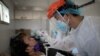 FILE - A nurse gets a swab from a man under observation for coronavirus disease (COVID-19) in a booth set up in a hospital parking lot in Manila, Philippines, April 15, 2020. 