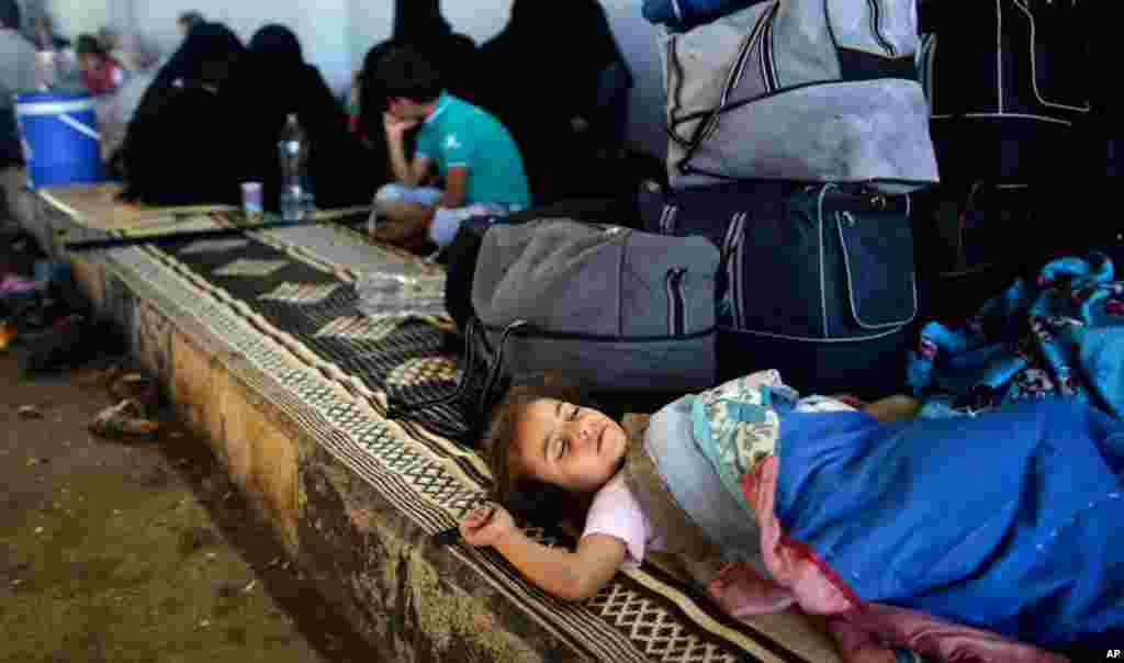 A Syrian girl who fled her home with her family due to fighting in Syria sleeps by her family's belongings at the Bab Al-Salameh border crossing in Azaz, in hopes of entering one of the refugee camps in Turkey, August 23, 2012.