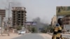 Un homme marche alors que de la fumée s'élève d'un quartier de Khartoum, au Soudan, le samedi 15 avril 2023.