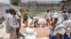 Les gens se rassemblent alors qu'un homme collecte des grains de blé lors d'une distribution de nourriture organisée par le gouvernement d'Amhara près du village de Baker, à 50 km au sud-est de Humera, dans la région du Tigré en Éthiopie, le 11 juillet 2021.
