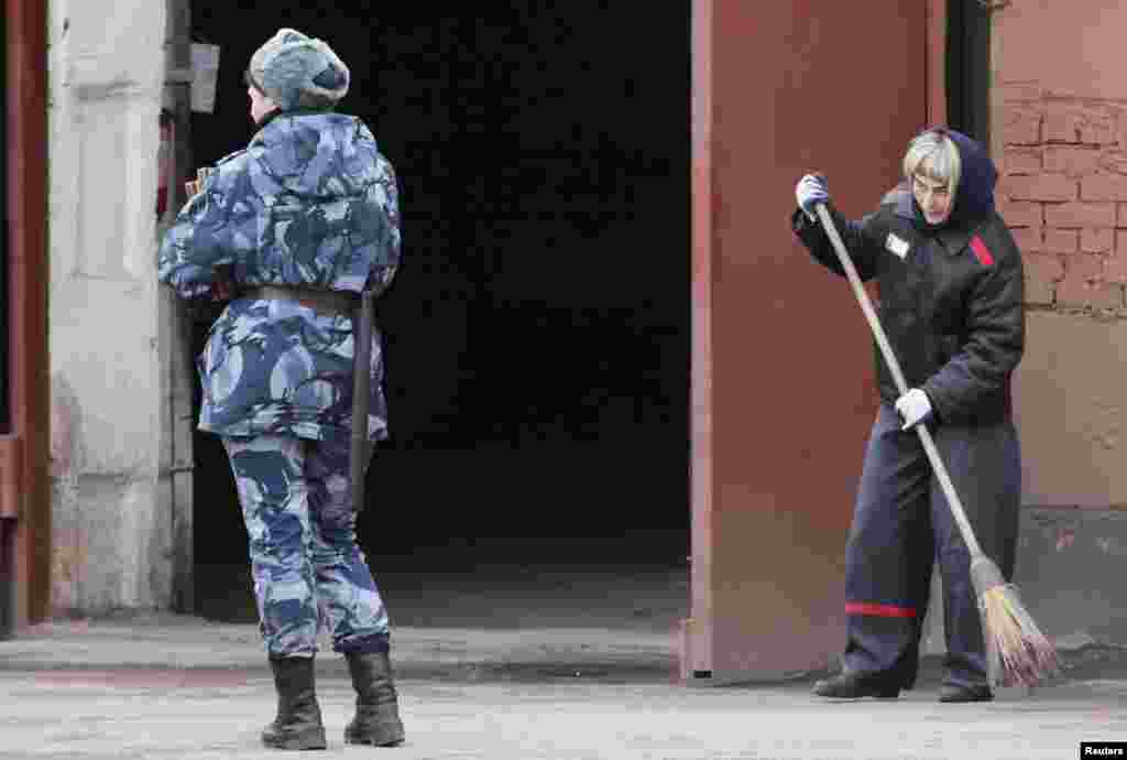 Seorang petugas penjara berdiri sementara seorang narapidana menyapu lantai di dalam kamp penjara khusus perempuan di kota Krasnoyarsk, Siberia Rusia.