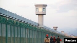 幾名工人在新疆一再教育營外走過。