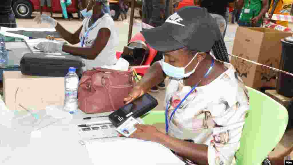 A poll worker verifies a voter's ID on election day in Accra, Ghana, Dec. 7, 2020. (Photo: Peter Clottey, Issah Ali / VOA)