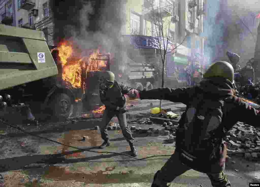 Demonstran anti-pemerintah melemparkan batu ke arah para pejabat Kementerian Dalam Negeri dalam sebuah protes dekat Gedung Parlemen di Kyiv (18/2). (Reuters/Gleb Garanich)