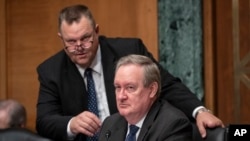 Senate Banking Committee Chairman Mike Crapo, R-Idaho, center, joined at left by Sen. Jon Tester, D-Mont., listens during a hearing on U.S. economic sanctions against Russia and whether the actions are effective, on Capitol Hill, Aug. 21, 2018. 