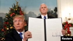 Presiden AS Donald Trump memegang proklamasi yang ia tandatangani yang menyatakan Amerika Serikat mengakui Yerusalem sebagai ibukota Israel dan akan memindahkan kedutaan besarnya ke Yerusalem, setelah selesai menyampaikan pidato di Gedung Putih di Washington, 6 Desember 2017.