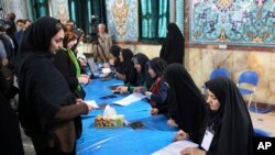 Peserta pemilu Iran (kiri) tiba di TPS untuk mengikuti pemungutan suara parlemen di Teheran, Iran (26/2). 