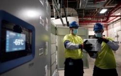 The temperature on a freezer reads -69°C as workers move boxes containing the Pfizer-BioNTech COVID-19 vaccines to be shipped at the Pfizer Global Supply Kalamazoo manufacturing plant in Portage, Michigan.