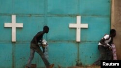 People hide from gunfire near church during firefight between African peacekeepers, fighters from the Christian "anti-balaka" militia, Bangui, Feb. 18, 2014.
