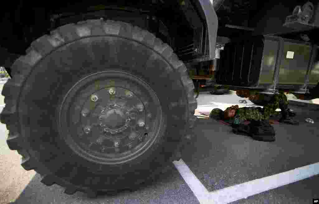 A Thai soldier lies under a truck to take a nap at National Anti-Corruption Commission office in Bangkok, Feb. 27, 2014. 