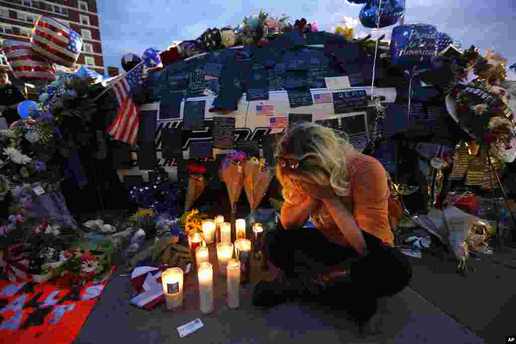 Tasha Lomoglio dari Dallas menangis setelah menyalakan lilin di memorial untuk menghormati para polisi yang tewas, di depan kantor polisi Dallas, Texas (9/7). (AP/Gerald Herbert)