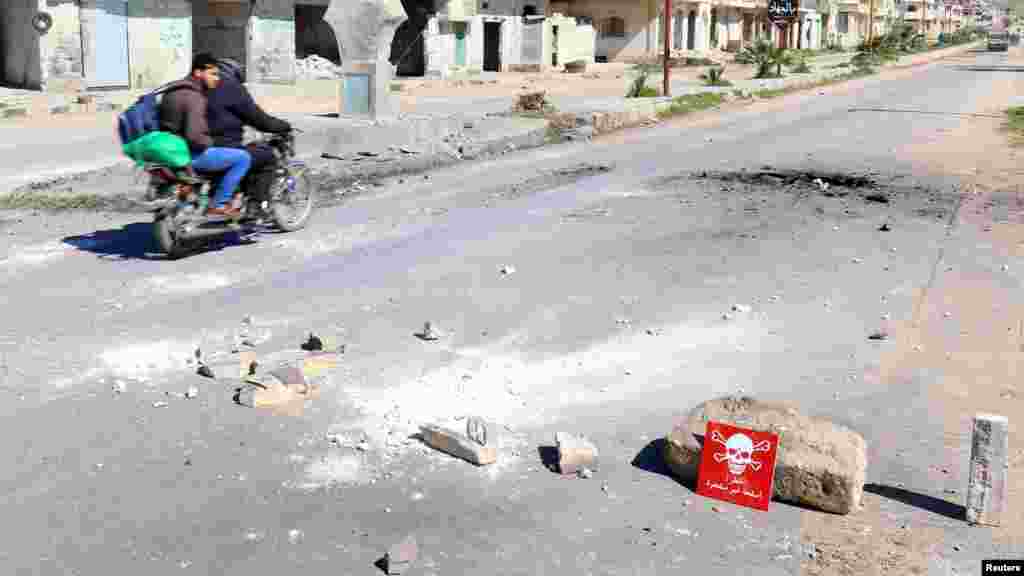 Deux hommes roulent une moto sur le lieu de l'attaque présumée chimique dans la ville de Khan Sheikhoun, le 5 avril 2017.