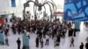 Activists march inside a conference center under a giant statue of a spider to demand urgent action to address climate change at the U.N. climate talks in Doha, Qatar, Friday, Dec. 7, 2012. 