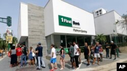 FILE - People wait to withdraw cash at a bank in the aftermath of Hurricane Maria, in San Juan, Puerto Rico, Sept. 27, 2017. On Nov. 29, 2018, Puerto Rico said it had finished its first debt-restructuring deal since its bankruptcy was announced more than three years earlier.