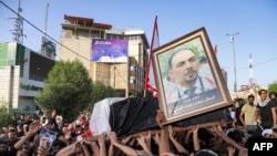 Para pelayat menyerukan slogan-slogan sambil menguzung peti jenazah aktivis anti-pemerintah Ehab al-Ouazni, saat prosesi pemakamannya di Kota Karbala, Minggu, 9 Mei 2021. Wazni tewas setelah ditembak orang tak dikenal di depan rmahnua.
