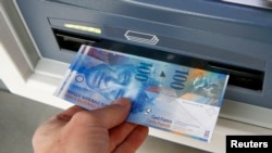 Seorang nasabah bank tengah menarik satu lembar uang pecahan kertas 100 franc di sebuah ATM Kreuzlingen, Swiss (Foto: dok).