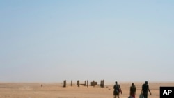 ARCHIVES - Trois hommes se dirigent vers l'Algérie après avoir franchi le poste frontière d'Assamaka, dans le nord du Niger, le dimanche 3 juin 2018.