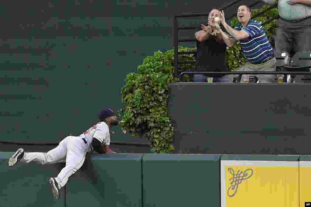 Boston Red Sox center fielder Jackie Bradley Jr., left, watches fans go for a ball hit by Baltimore Orioles' Jonathan Villar for a grand slam during the second inning of a baseball game, May 6, 2019, in Baltimore, Maryland.