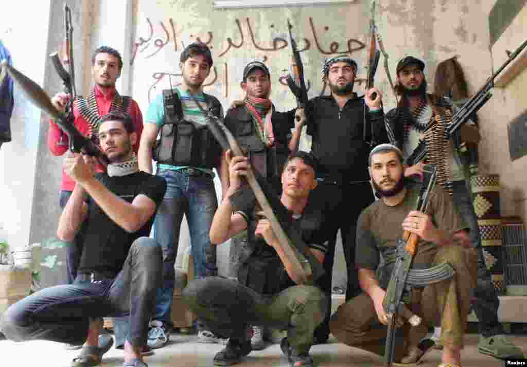 Rebel fighters pose with their weapons in Homs, Syria, July 1, 2012.