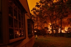 Firefighting crews from the Rural Fire Service, NSW Fire and Rescue and National Parks and Wildlife Service officers fight a bushfire encroaching on properties near Lake Tabourie, Australia, Dec. 5, 2019.